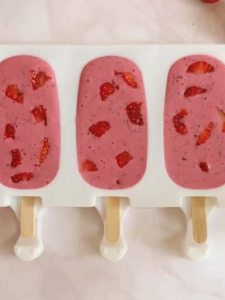 three pink strawberry popsicles in a silicone mold
