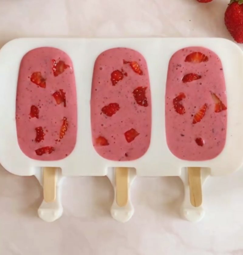 three pink strawberry popsicles in a silicone mold